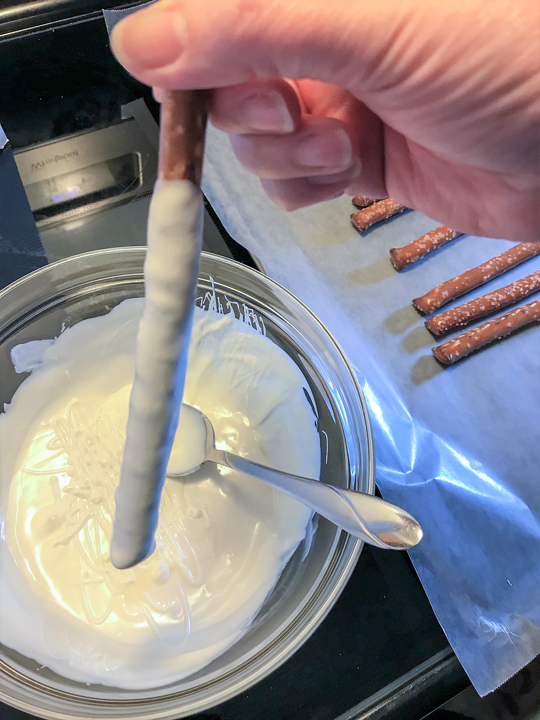 dipping pretzel in the bowl of frosting