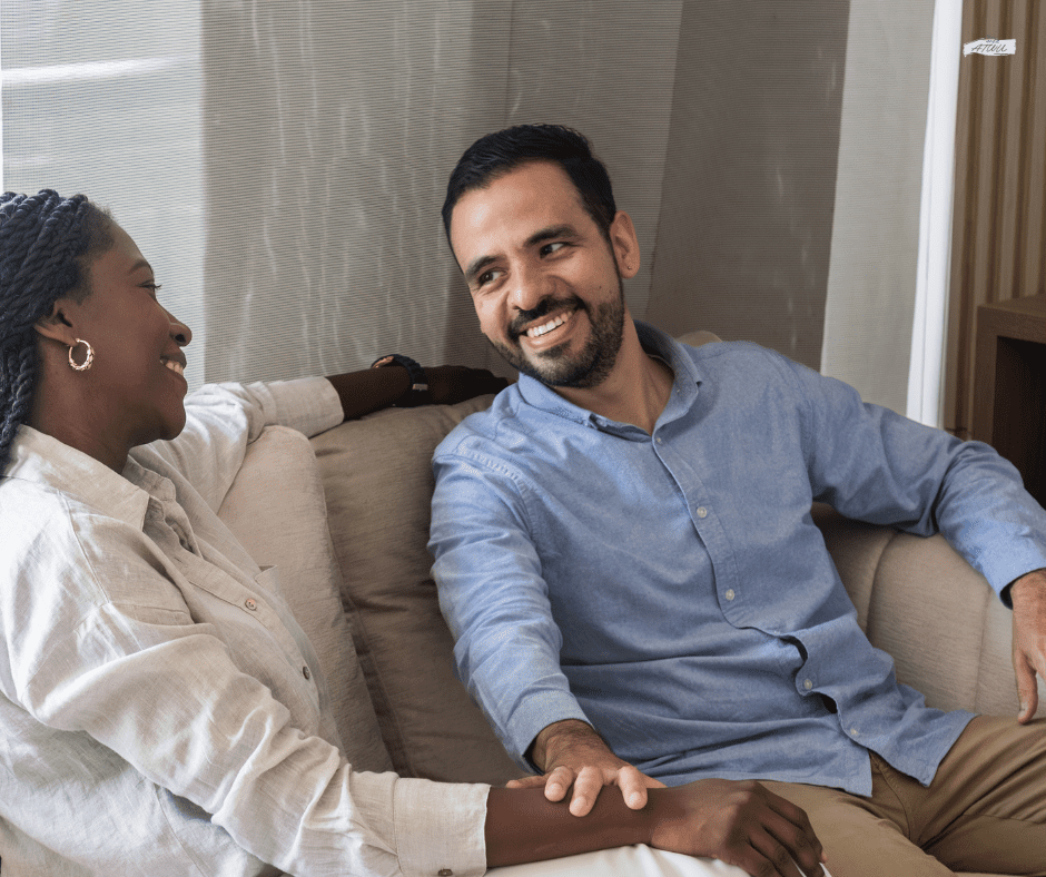mixed race couple sitting on a couch talking and smiling